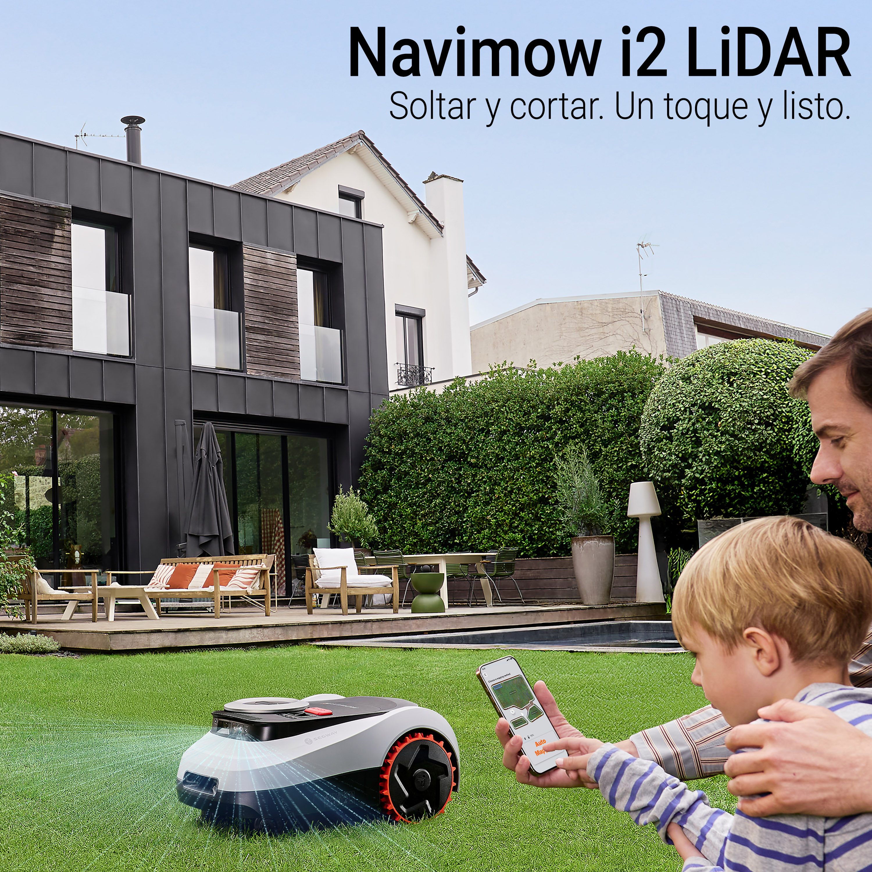 La imagen muestra un robot cortacésped Navimow i2 LiDAR en un jardín bien cuidado, con una casa moderna de fondo. El robot está en el césped, mientras un padre y su hijo observan y controlan el dispositivo a través de un teléfono móvil. La escena transmite un ambiente familiar y tecnológico, con colores verdes del césped y tonos neutros en la casa. El ángulo de la toma resalta tanto el producto como la interacción entre el padre y el niño.
