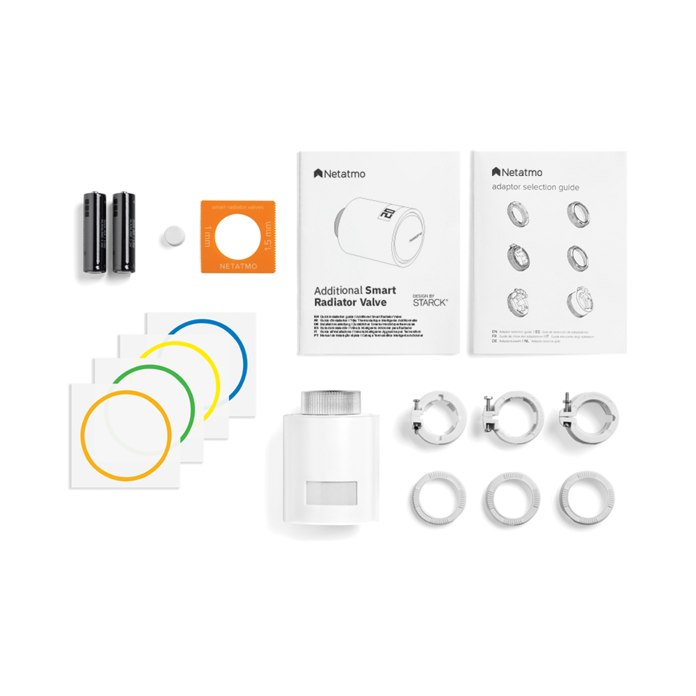 La imagen muestra un conjunto de productos de la marca Netatmo, específicamente una válvula termostática inteligente adicional para radiadores. El producto se presenta en un ambiente limpio y ordenado, con un fondo blanco que resalta los elementos. Se pueden ver la válvula, baterías, guías de instalación y varios adaptadores, todos organizados de manera clara. Los colores predominantes son el blanco y el gris, con detalles en naranja y verde en los accesorios.