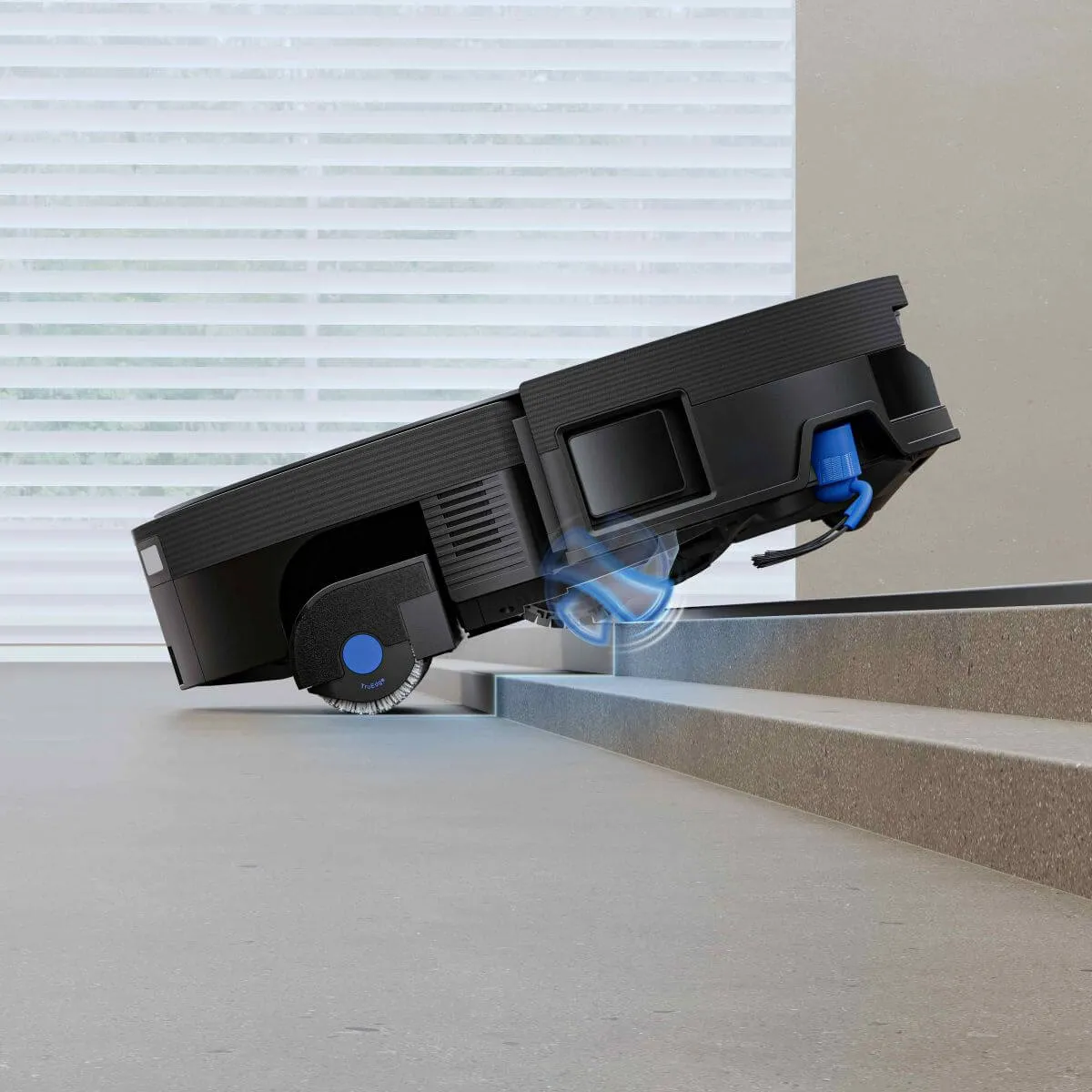La imagen muestra un robot aspirador de la marca Ecovacs, modelo DEEBOT X12 OMNICYCLONE, en un entorno doméstico. El dispositivo está diseñado para superar obstáculos, como escaleras, gracias a su tecnología avanzada, lo que lo hace ideal para la limpieza automatizada del hogar.